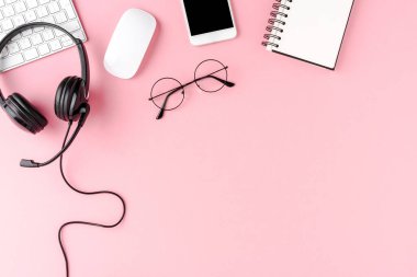 Pembe arkaplan üzerinde yardım kulaklığı ve bilgisayar aksesuarları olan çağrı merkezi masaüstüName
