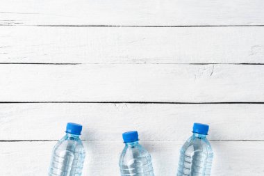 Küçük plastik şişelerdeki maden suyu beyaz ahşap arka planda, kopyalanmış. Üst görünüm