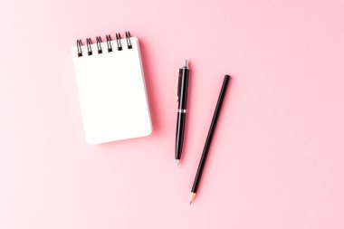 İş geçmişi, boş defterler ve pembe masa üzerindeki kalemler. Ofis masaüstü