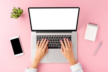 Kadın elleri boş ekranla dizüstü bilgisayarda çalışıyor. Aksesuarlı ofis masası. Üst görünüm