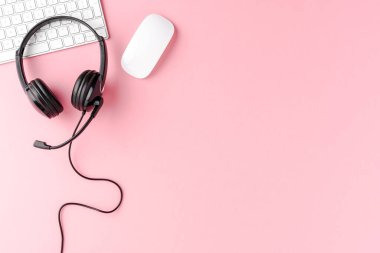 Pembe masaüstünde bilgisayar aksesuarları olan müşteri hizmetleri kulaklığı. Çağrı merkezi kavramı