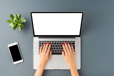 Kadın elinin gri arka planda boş ekranlı dizüstü bilgisayarı kullanırken çekilen resmi. Modern çalışma alanı konsepti. Düz yatıyordu