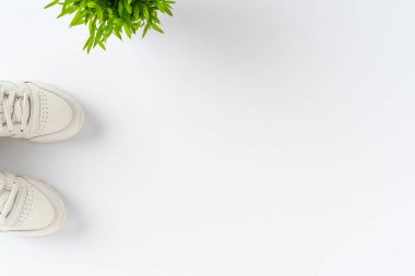 Tepeden çekilen spor ayakkabılı ve beyaz arka planda çiçekli telif alanı olan kıyafetler. Kadın yaşam tarzı. Üst görünüm