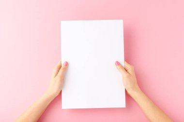 Genç kadın elleri pembe arka planda boş kağıt örtüler gösteriyor. Model