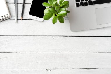 Laptop, akıllı telefon, defter, kalem ve beyaz ahşap masaüstünde küçük sulu bir ofis masası. İş geçmişi