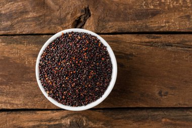 Kırsal ahşap masadaki kasede siyah kinoa tohumları. Üst görünüm