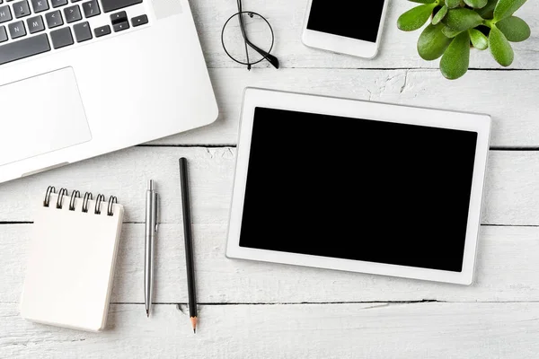 Digital tablet with empty screen on white wooden background with business accessories. Office desktop