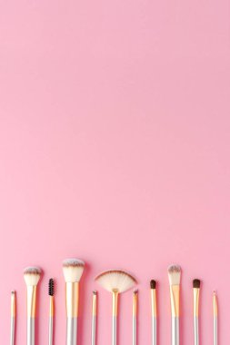 Pembe arkaplanda makyaj fırçaları