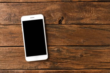 Kırsal ahşap arka planda boş ekranlı cep telefonu. Üst görünüm