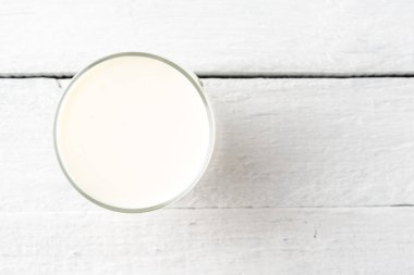 Beyaz ahşap masada bir bardak süt. Kapat.