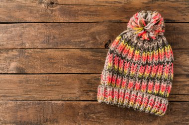 Rengarenk kış şapkalı, kabataslak ahşap arkaplanlı, kopyalanmış bir ponpon.