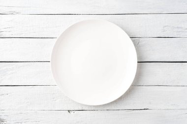 Tahta masadaki boş beyaz tabağın üstünden. Kapat.