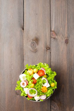 Tahta arka planda kasede sağlıklı salata. Üst görünüm