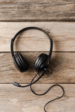 Masa başı çağrı merkezi kavramına yardım. Kopyalama alanı ile ahşap arkaplan üzerine kulaklık