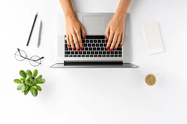 Woman hands working on laptop on white table with accessories. Business background. Flat lay