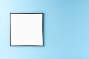 Mavi duvarda asılı boş bir fotoğraf çerçevesi. Model