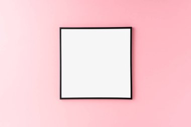 Boş fotoğraf çerçevesi pembe duvarda asılı. Model