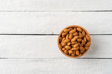 Kabuktaki soyulmuş bademleri beyaz ahşap masada resmedeceğiz. Sağlıklı atıştırmalıklar