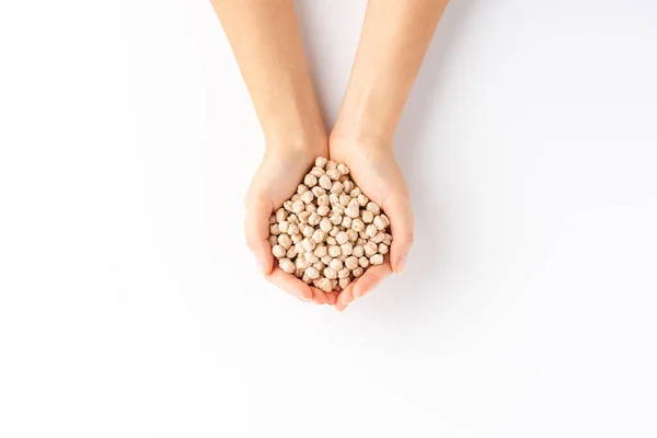 白い背景に隔離されたひよこ豆の豆を保持している女性の手のオーバーヘッドショット — ストック写真