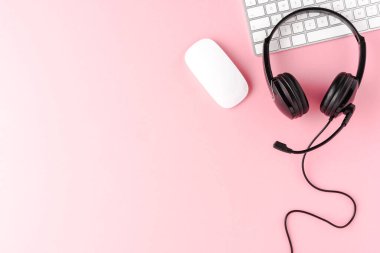 Pembe masaüstünde bilgisayar aksesuarları ve kopyalama alanı olan müşteri hizmetleri kulaklığı. Çağrı merkezi kavramı