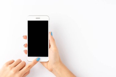 Mavi tırnaklı bir kadın beyaz arka planda boş ekranlı akıllı telefon kullanıyor. Üst görünüm