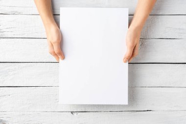 Kopyalama alanı olan kağıt çarşaf tutan genç kadın elleri. Üst görünüm