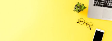 Sarı arka planda iş aksesuarları ve kopyalama alanı olan zarif bir çalışma alanı. Ofis masaüstü. Pankart