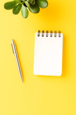 Ofis masaüstü boş defter ve sarı arka planda kalemle. İş konsepti. Üst görünüm