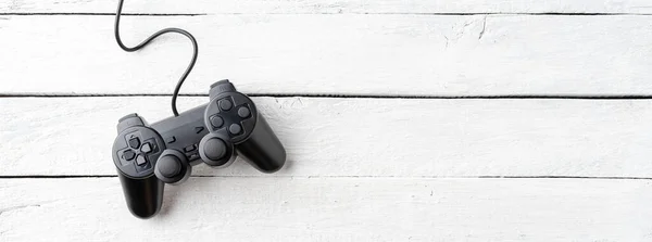 Black video game console on white wooden background with copyspace. Top view. Banner