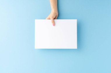 Mavi arka planda boş kağıt kağıtlar gösteren bir kadın eli. Kapat. 