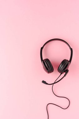 Pembe arka planda müşteri hizmetleri kulaklığı. Çağrı merkezi kavramı