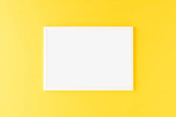 White picture frame on yellow background. Mockup with copyspace