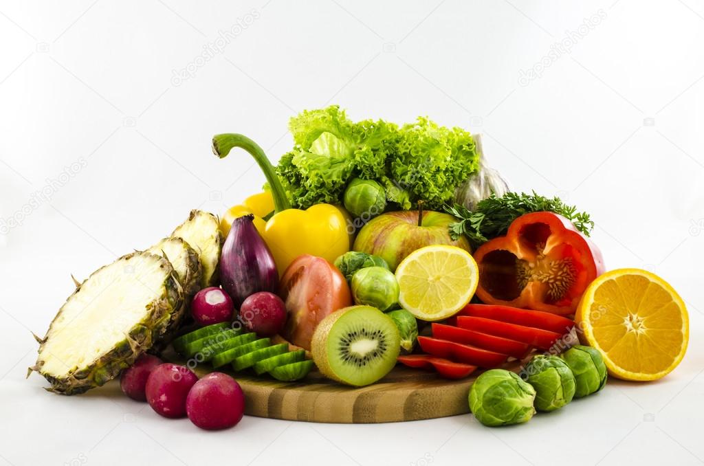 Composition of fruits and vegetables on wooden board. Cut and sliced