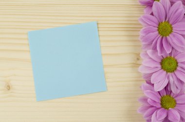 Boş Mavi kart ve ahşap arka plan üzerinde pembe çiçekler