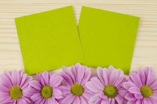 Üres zöld kártya és a rózsaszín virágok, fából készült háttér — Stock Fotó