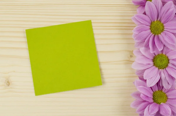 Üres zöld kártya és a rózsaszín virágok, fából készült háttér — Stock Fotó