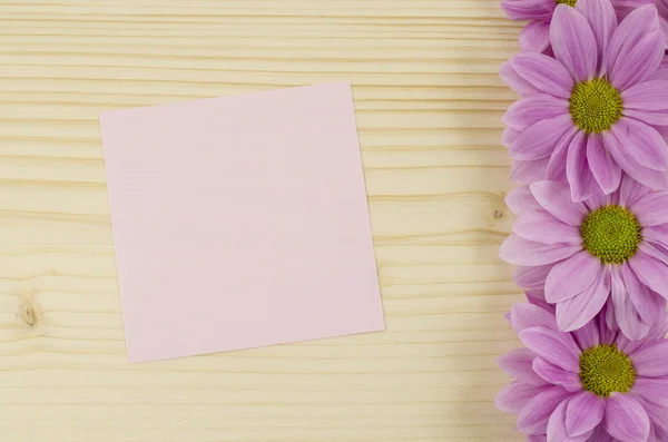 Cartão rosa em branco e flores cor-de-rosa sobre fundo de madeira — Fotografia de Stock