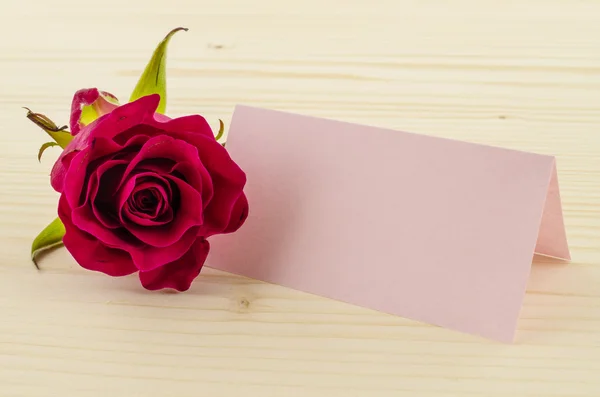Rosa flor con tarjeta de invitación en blanco sobre fondo de madera — Foto de Stock