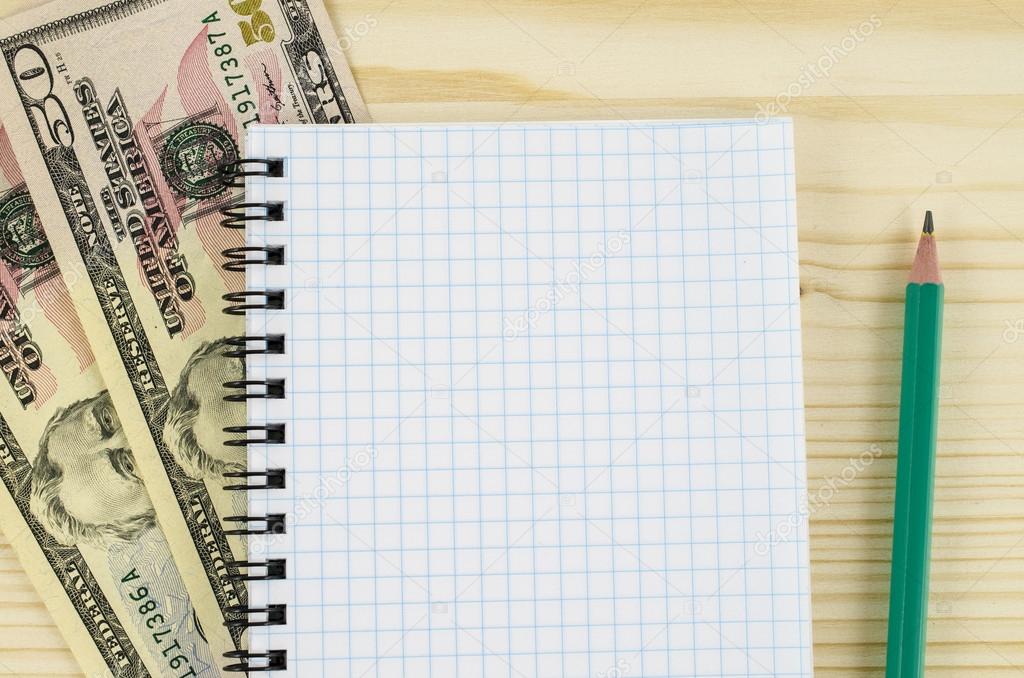 Blank notebook, pencil and dollars on wooden table