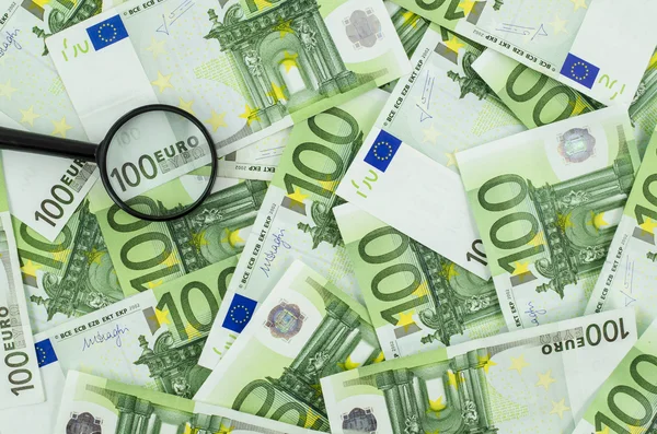 Lupa sobre fondo de billetes en euros — Foto de Stock