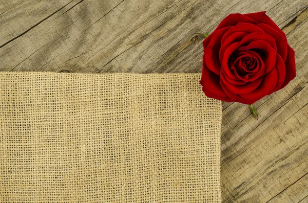 Juta, zsákvászon textúra Rózsa virág a régi fából készült asztal — Stock Fotó