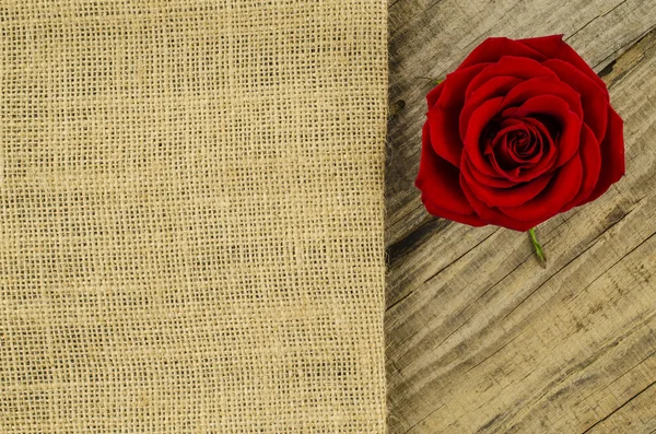 Juta, zsákvászon textúra Rózsa virág a régi fából készült asztal — Stock Fotó