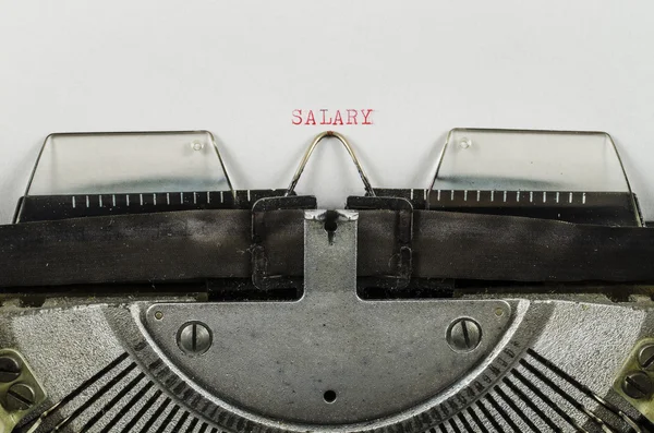 Palavra salarial impressa em uma velha máquina de escrever — Fotografia de Stock