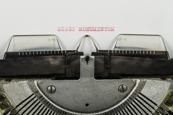Exegi monumentum word printed on an old typewriter — Stock Photo, Image
