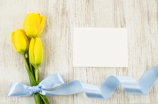 Cartolina vuota, fiori e nastro blu su fondo di legno — Foto Stock
