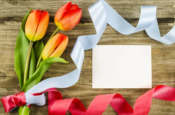 Empty postcard, colorful flowers and ribbon on wooden background — Stock Photo, Image