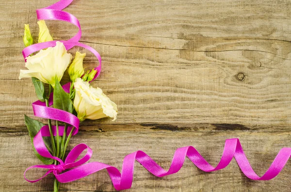 Prázdné dřevěné pozadí s barevnými květy a růžovou stuhou — Stock fotografie