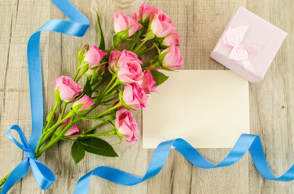 Empty postcard, flower and blue ribbon on wooden background — Stock Photo, Image