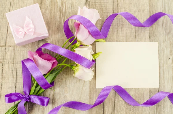 Empty postcard, flower and purple ribbon on wooden background — Stock Photo, Image