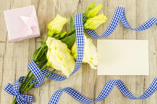 Prázdná pohlednice, květin a modrou stuhu na dřevěné pozadí — Stock fotografie